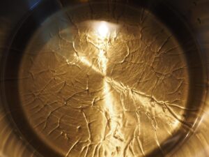 Un cucchiaio d'acqua viene versato nell'olio caldo per evitare che il soffritto bruci.