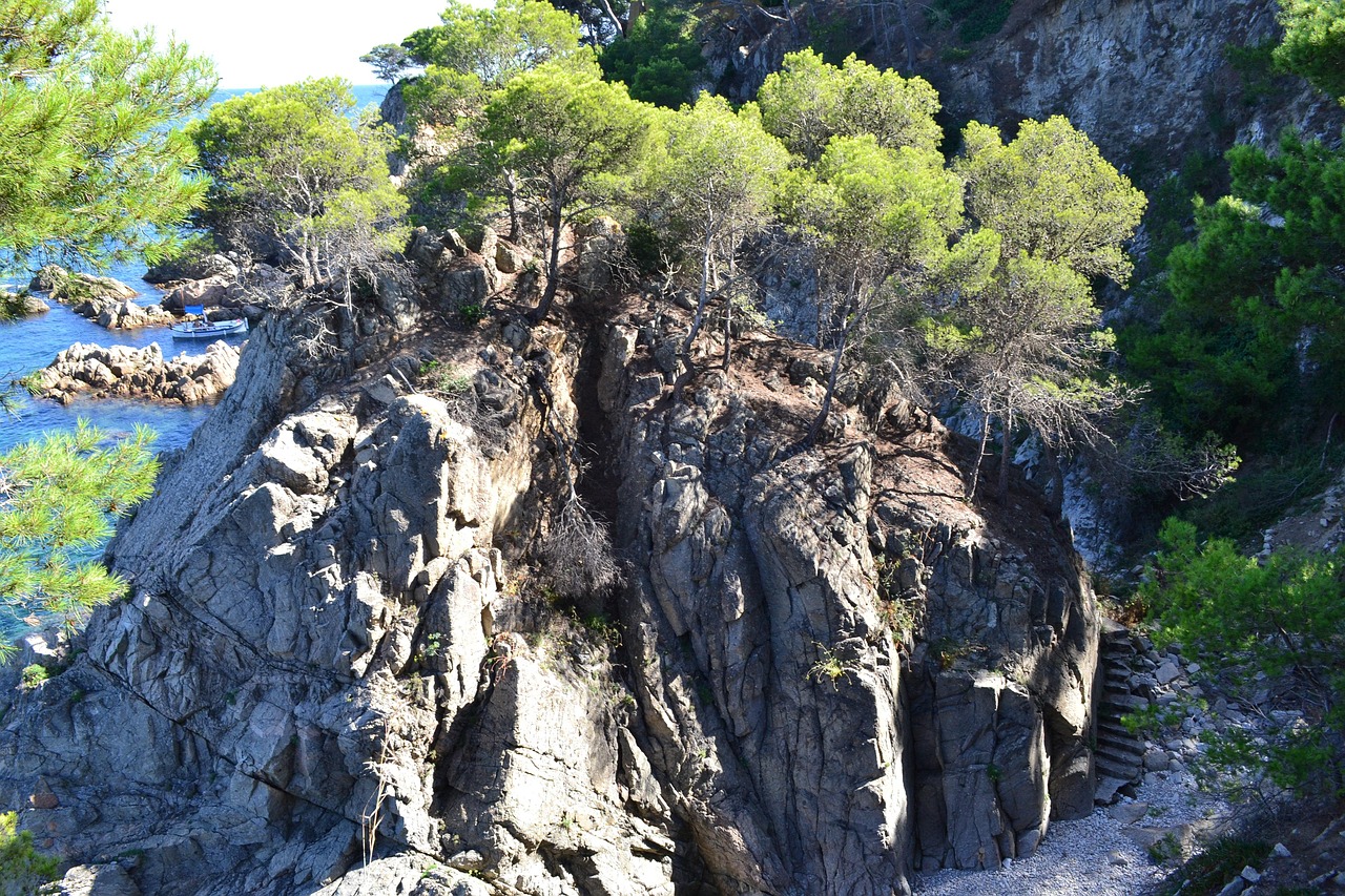 Vista panoramica della grotta di Nettuno e dell'Escala del Cabirol, con mare blu intenso sullo sfondo.